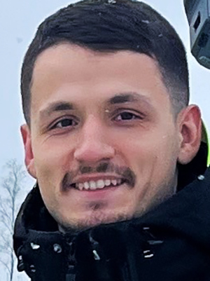 En ung man med m&ouml;rkt h&aring;r ler